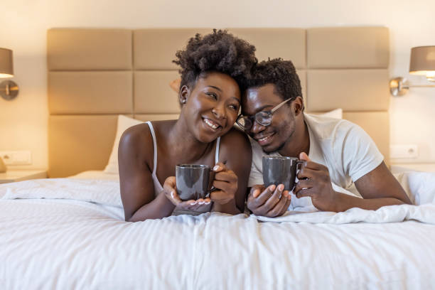 Affectionate couple enjoying morning coffee and cuddling in bed. Cropped shot of an affectionate young couple having coffee in their bedroom in the morning. Couple sharing a coffee in bed.